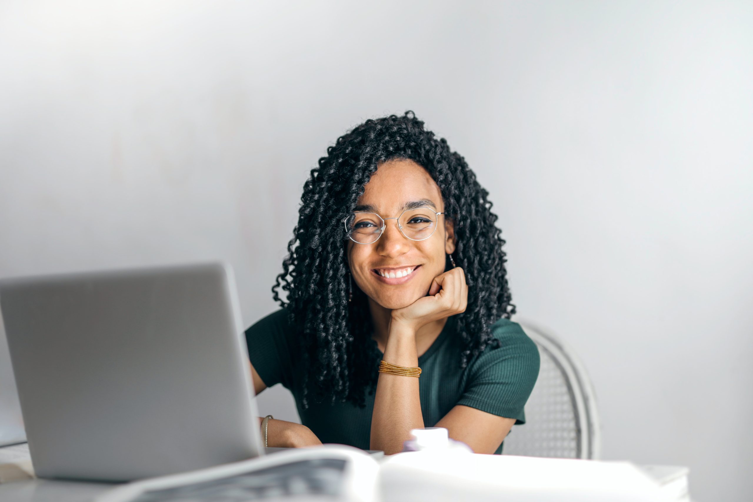 Femme assise devant son ordinateur en train de sourire.